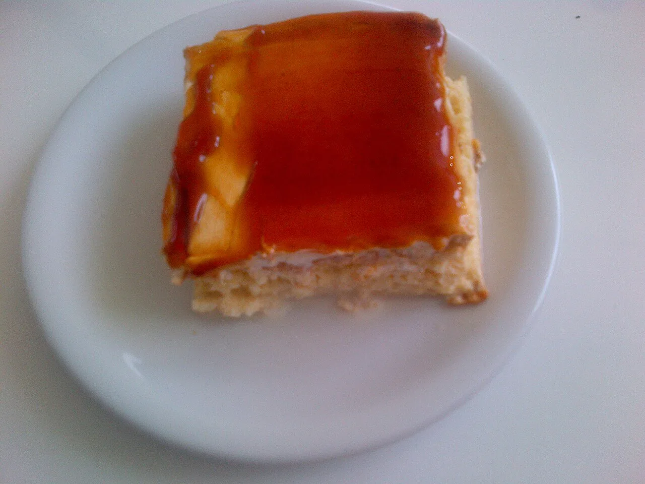 A slice of trileçe milk cake topped with caramel sauce.