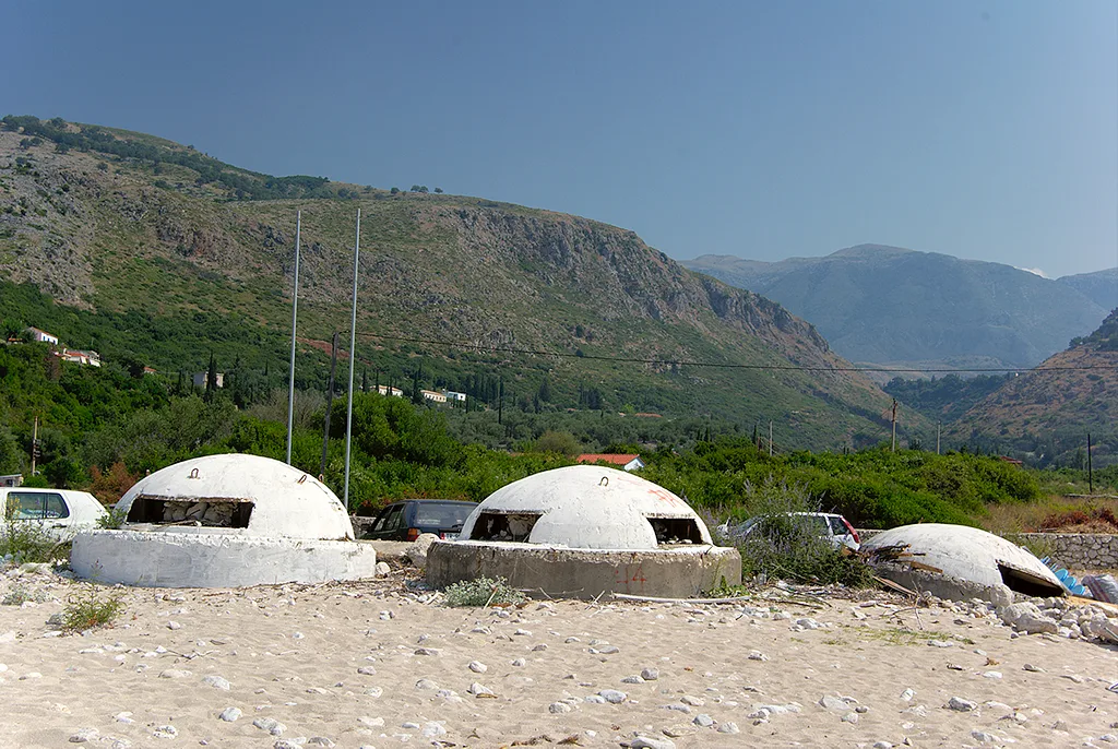 Concrete bunkers on the shore near Himarë below the coastal mountains.