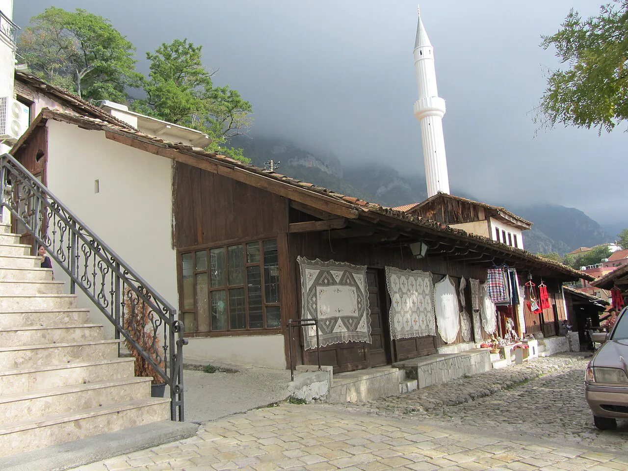 A traditional wooden shopfront in the Krujë bazaar with a minaret behind.