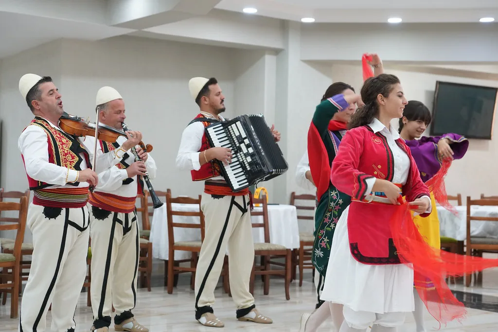Musicians and dancers in traditional Albanian costume performing folk music.