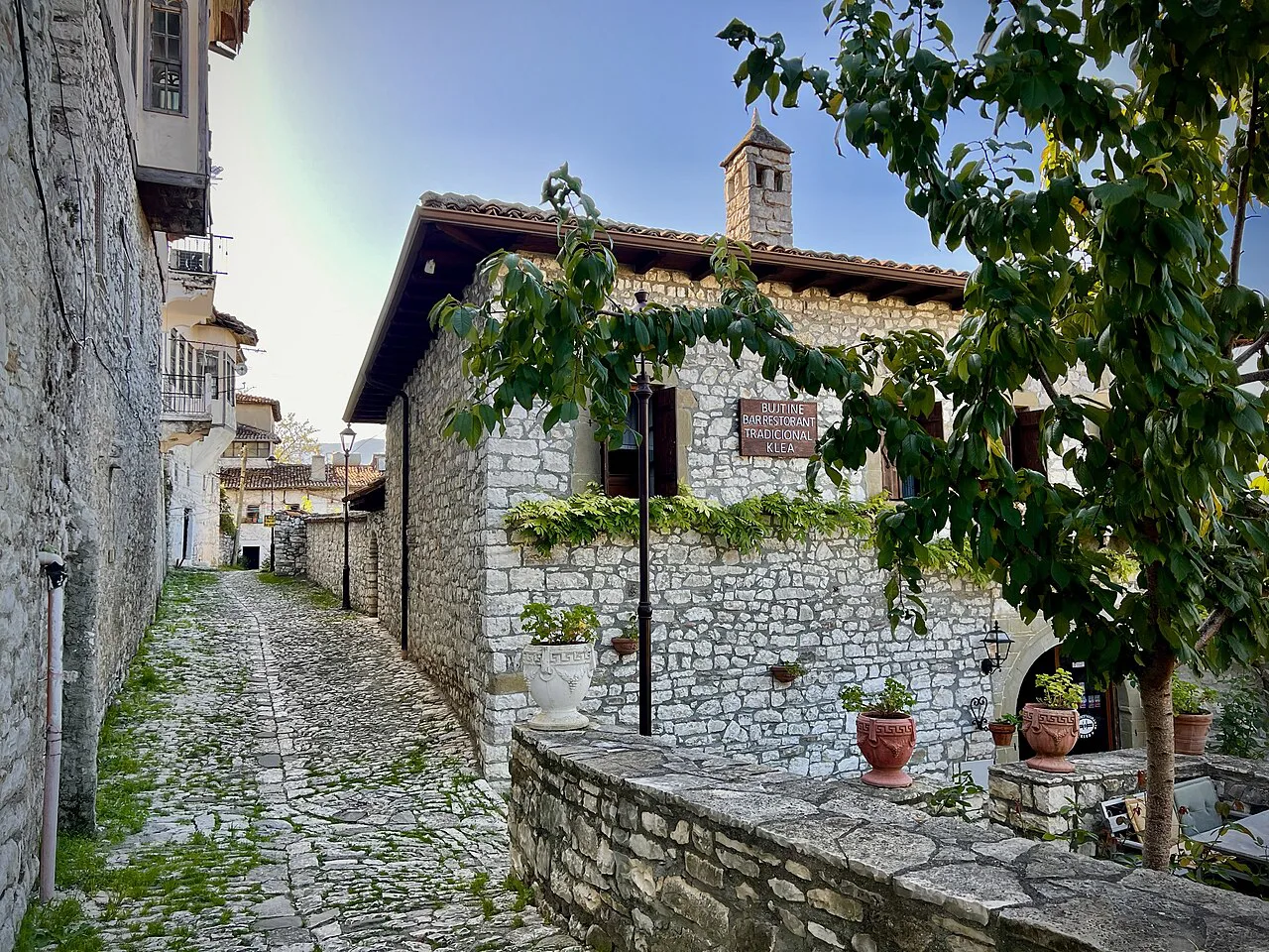A cobbled lane past stone houses leading to a traditional restaurant in Berat.
