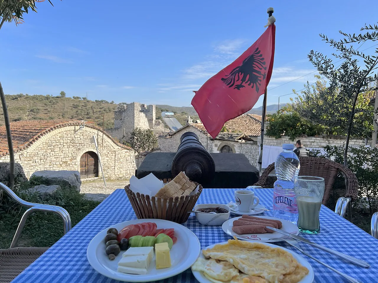 A meal laid out on a terrace beside an Albanian flag in Berat.