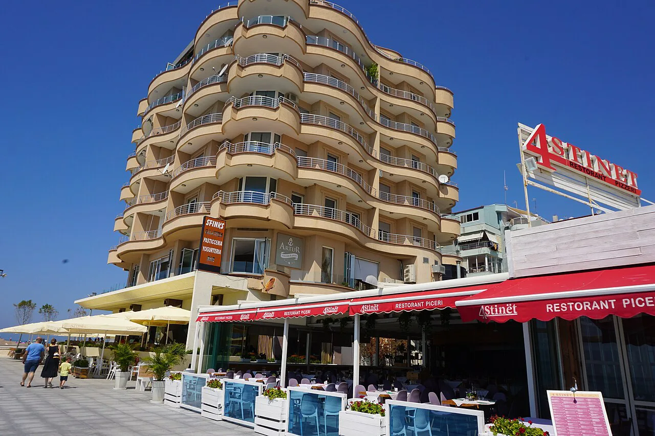 Restaurant terraces beneath apartment blocks on the Durrës seafront promenade.