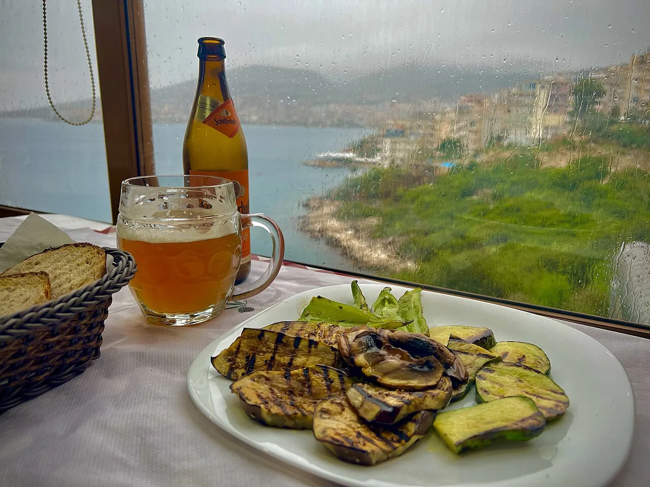 Grilled vegetables and a beer at a table overlooking Sarandë.