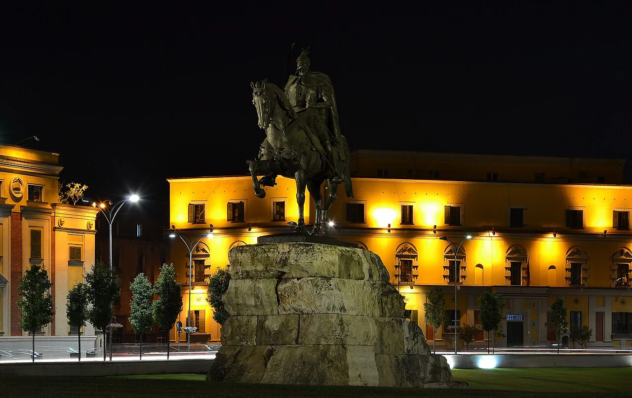 The Skanderbeg monument in Tirana's Skanderbeg Square, lit up at night.