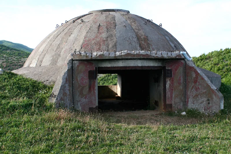 A concrete dome bunker on a grassy hillside in Albania.