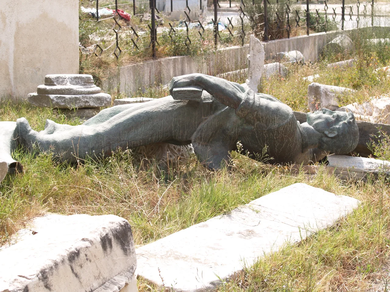Ancient stone fragments and a fallen statue in the garden of the Durrës Archaeological Museum.