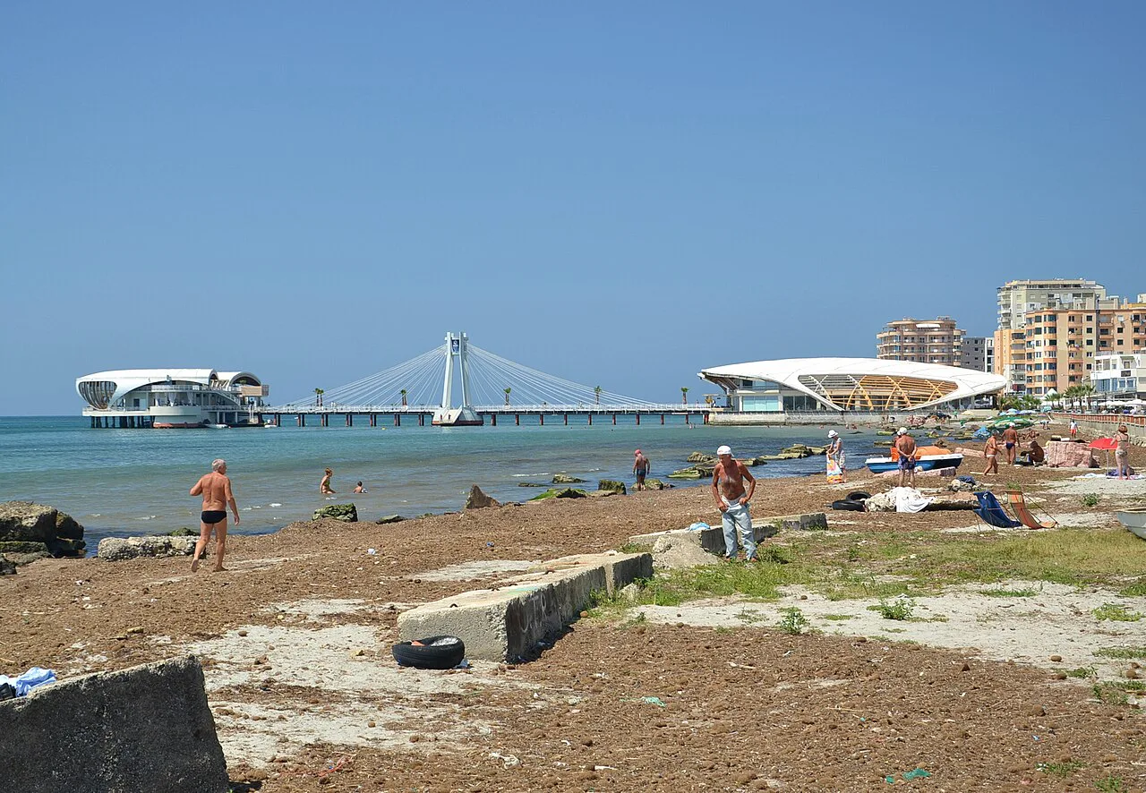Durrës beach with the seafront pier and promenade buildings behind.