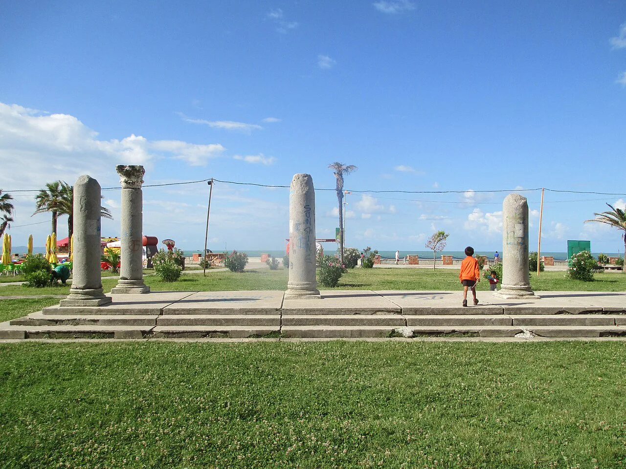 Ancient columns on a lawn beside the beach promenade in Durrës.