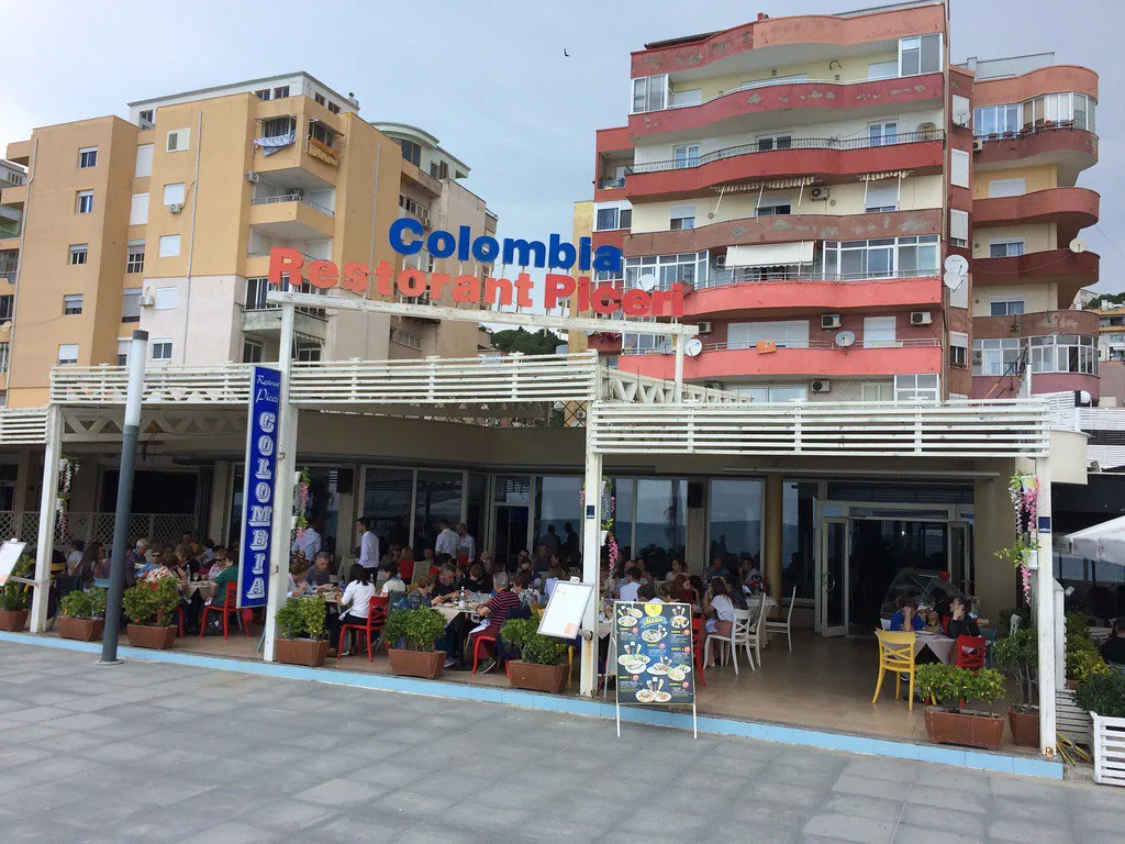 A seafront restaurant terrace beneath apartment blocks in Durrës.