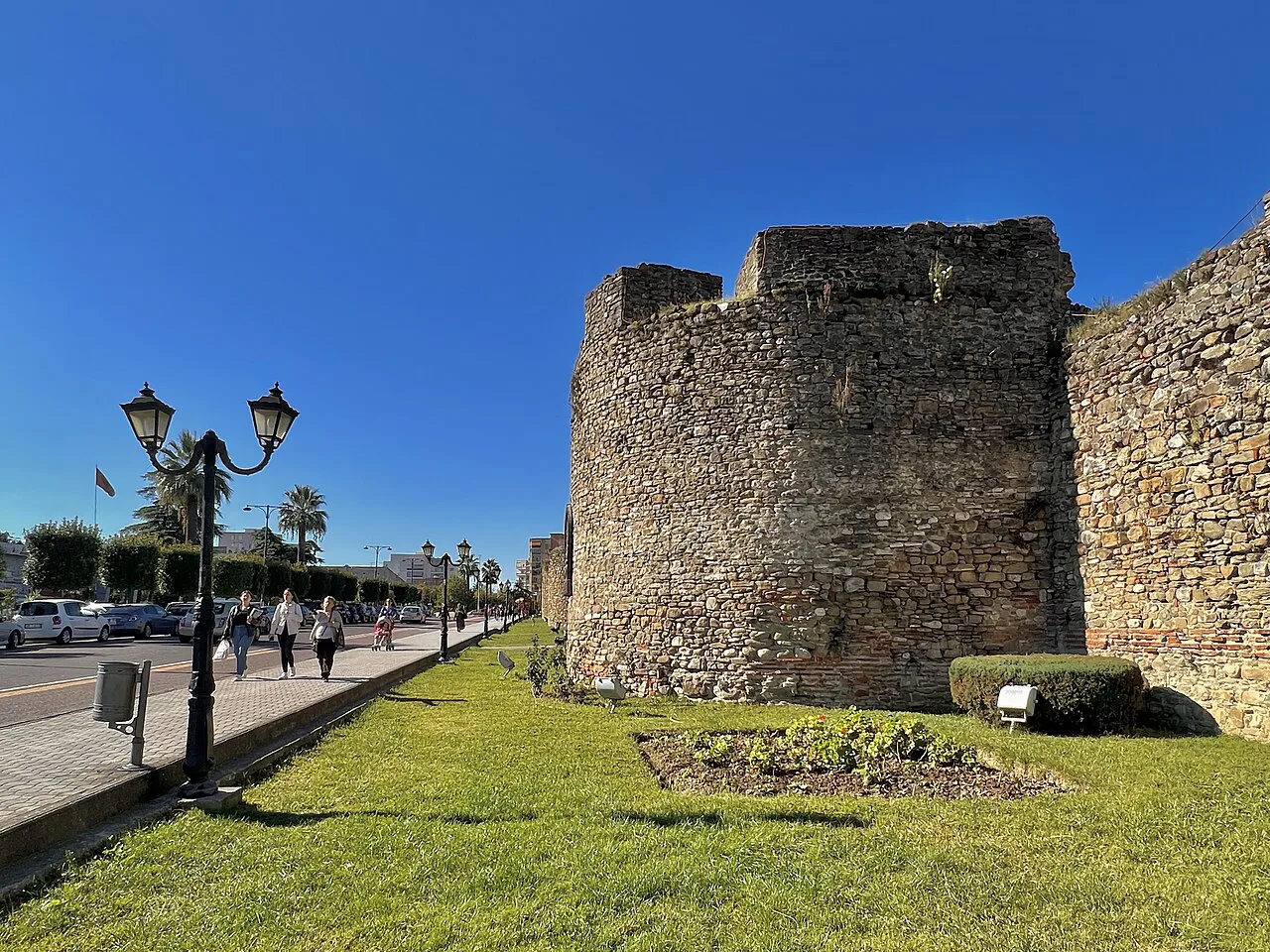 A tower of Elbasan Castle beside a tree-lined promenade.