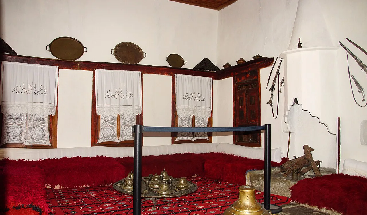 A traditional room with red cushions inside the Ethnographic Museum of Berat.