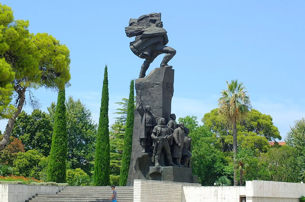 The Independence Monument in Vlorë framed by cypress trees.
