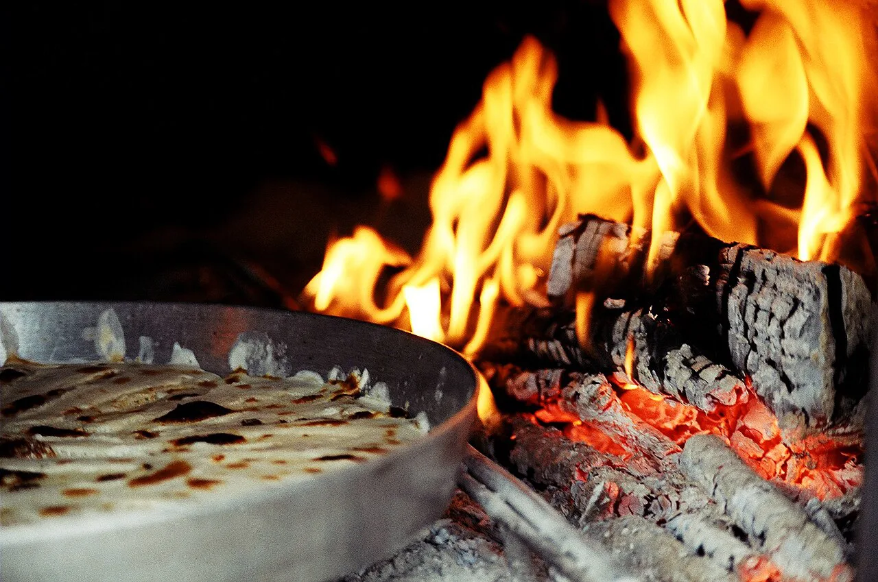 Flija baking beside hot embers in the traditional way.