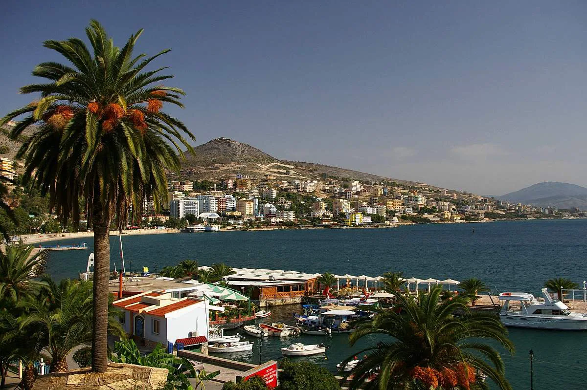 Sarandë's harbour and bay framed by palm trees.