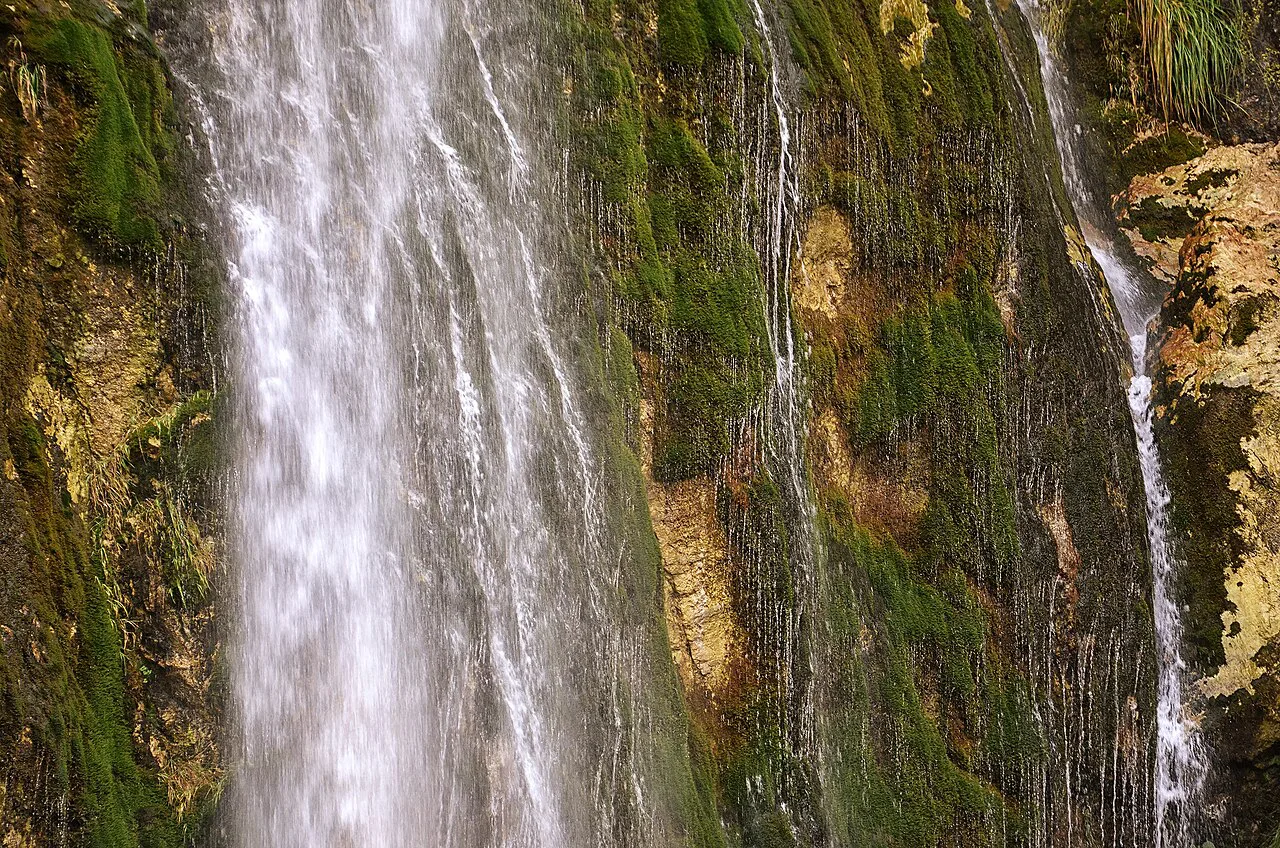 Water cascading down the mossy rock face of Grunas Waterfall in Theth.