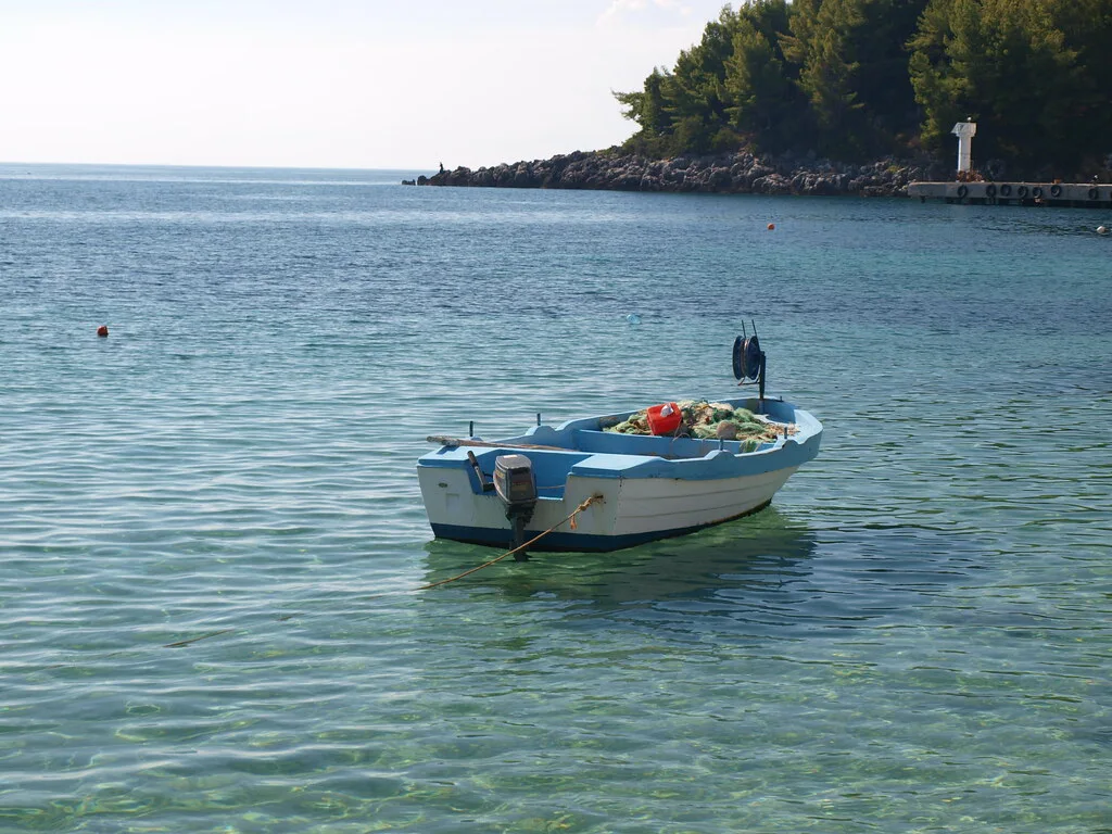 A small boat moored in clear turquoise water off the coast near Himarë.