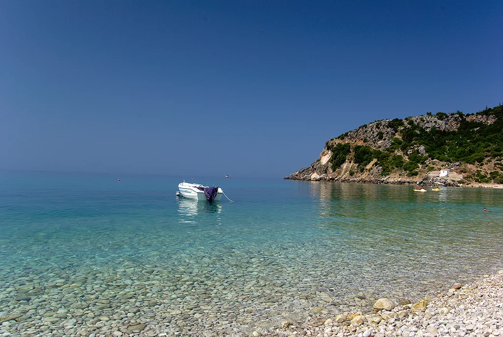 A boat floating in a quiet pebble-beach cove near Himarë.