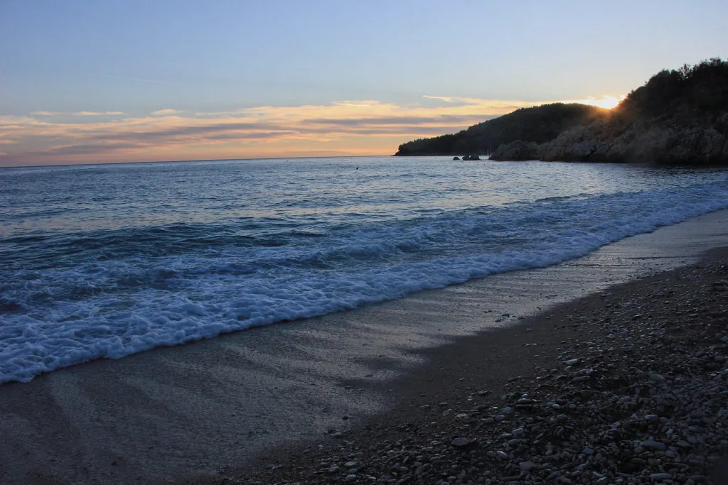 Waves breaking on the beach at Himarë as the sun sets behind the headland.