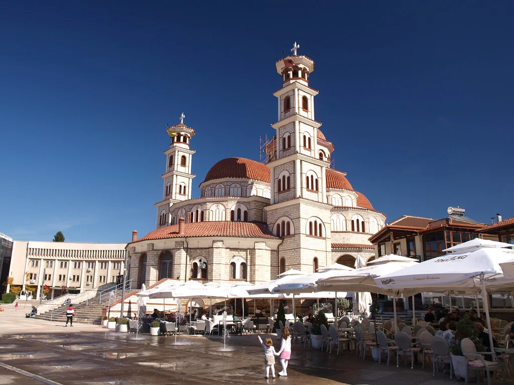 The Resurrection Cathedral in Korçë with café umbrellas in the square in front.