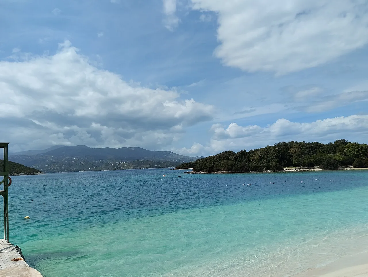 Turquoise water and a wooded islet at Ksamil beach.