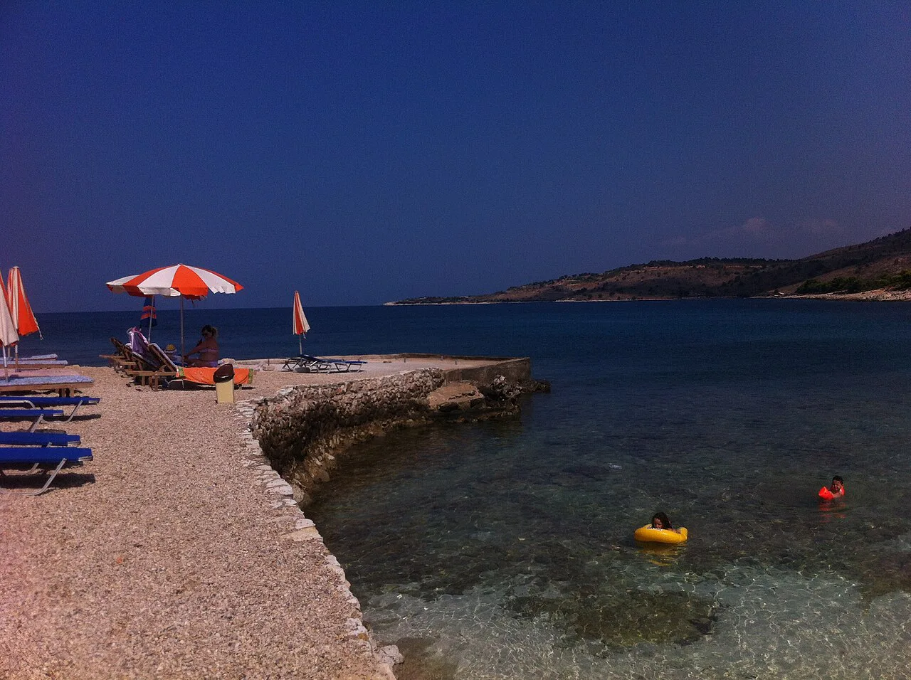 Sunbeds and a rocky shore on the waterfront at Ksamil.
