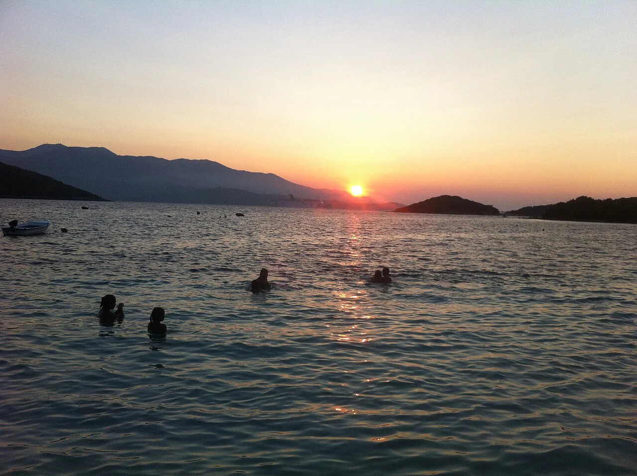 Swimmers in the sea at Ksamil at sunset.