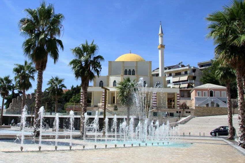 The Great Mosque of Durrës behind a fountain and palm trees.