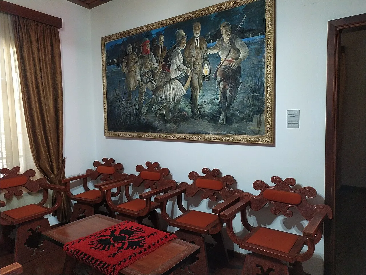 A painting above carved chairs inside the Independence Museum in Vlorë.