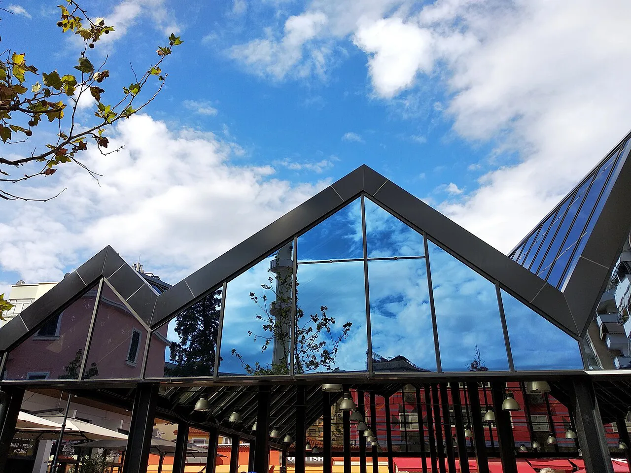 The glass roof of the New Bazaar in Tirana against a blue sky.