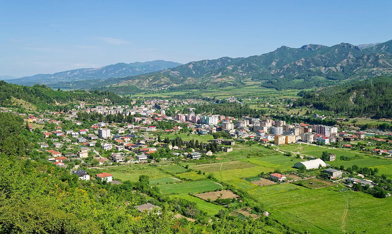 A panorama of Përmet set among fields and mountains.