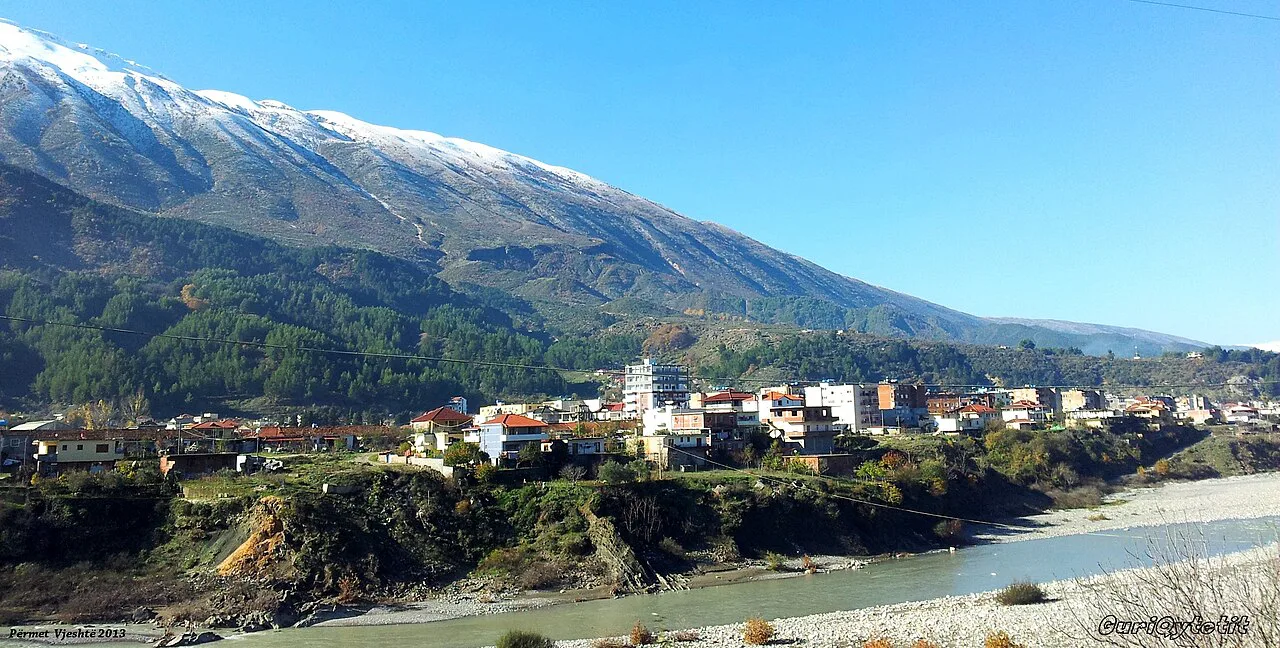 The river and town of Përmet below a snowy mountain ridge.