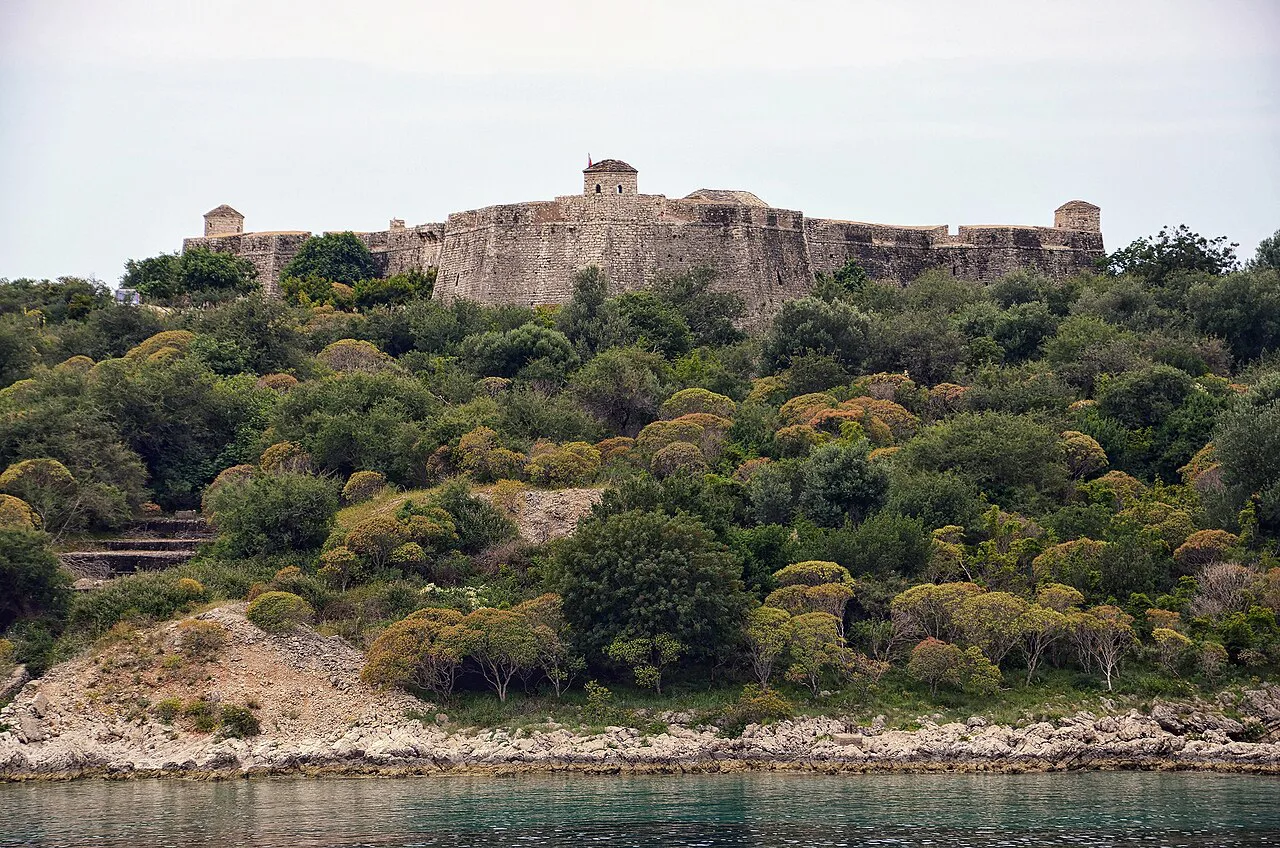 Porto Palermo Castle above the wooded shore.