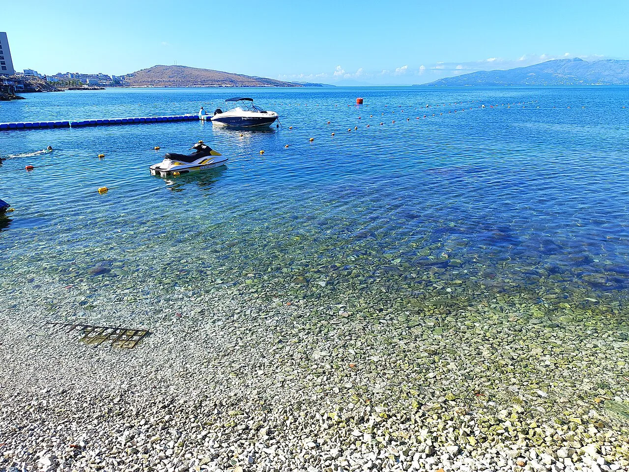 Boats moored off a pebble beach in Sarandë.