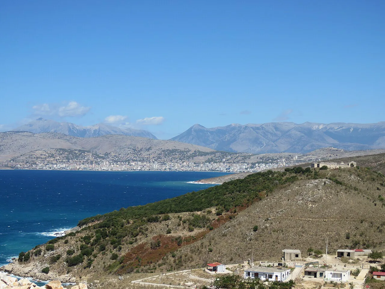 The coast at Sarandë seen from the south, with mountains across the water.