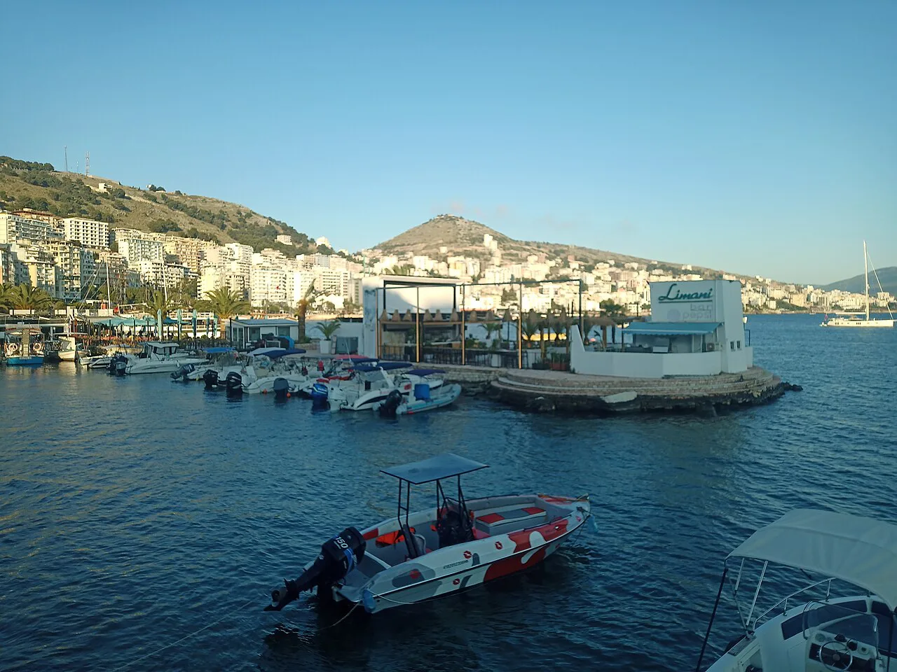 Boats in the harbour in central Sarandë with the town behind.