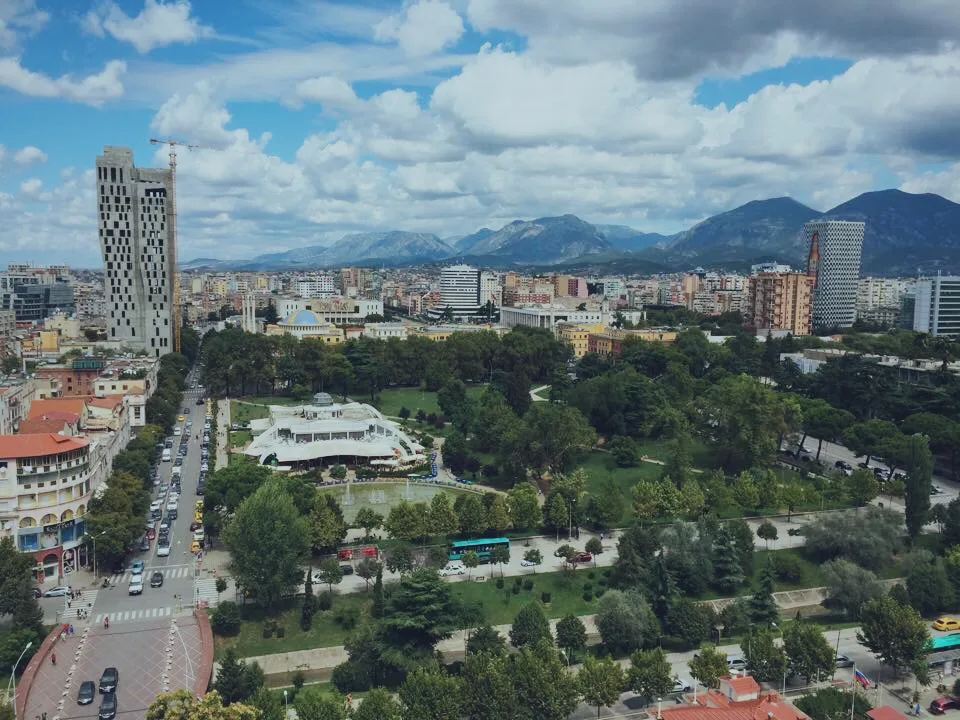 Rinia Park in central Tirana, seen from above with mountains beyond.