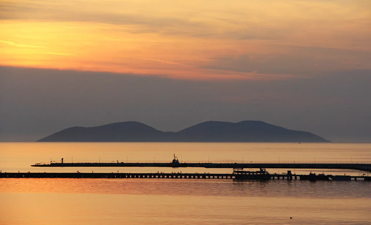 Sunset over the Bay of Vlorë with a long pier in the foreground.