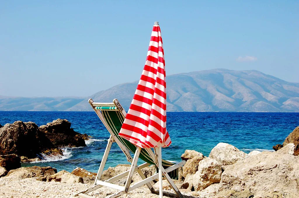 A red-and-white parasol on the rocky shore at Jonufer near Vlorë.