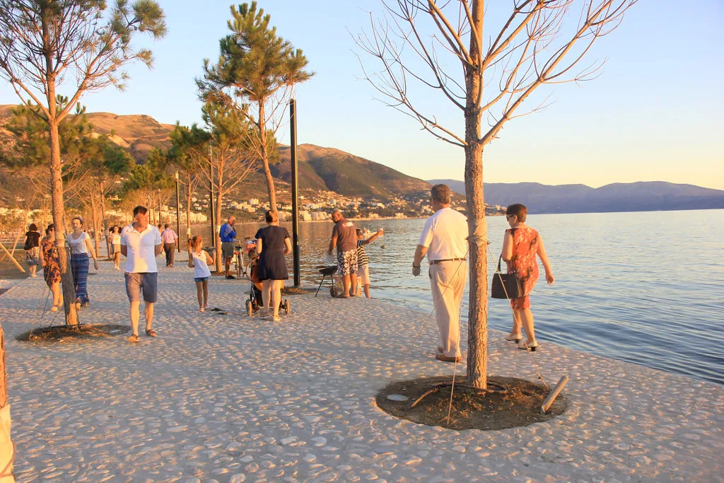 People strolling along the seafront promenade in Vlorë at sunset.